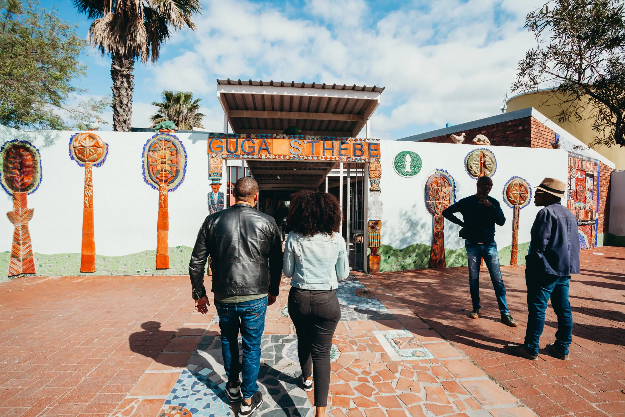 Visitors walk into the Guga S'thebe arts centre in Langa, its white walls lined with ceramic murals